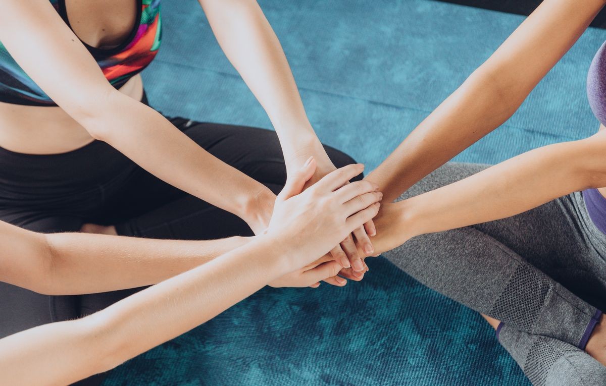 Close up of yoga girls join hand as a team before playing yoga in class at gym. Excercise and Healthy concept